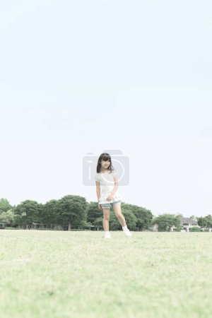 Foto de Linda chica japonesa caminando en el parque de verano, retrato diurno de un niño divertido divirtiéndose al aire libre - Imagen libre de derechos