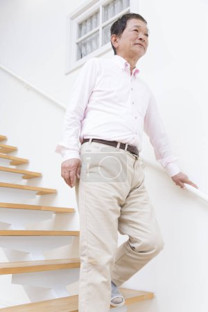 Photo for Senior asian man in white shirt walking on stairs - Royalty Free Image