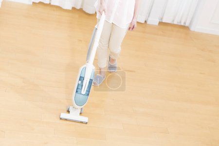 Téléchargez les photos : Femme nettoyage sol à la maison avec aspirateur - en image libre de droit