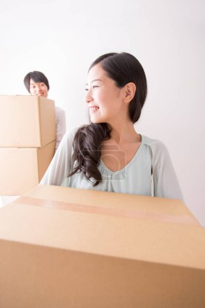Foto de Joven asiático hombre y mujer con cartulina cajas moviéndose en nuevo apartamento - Imagen libre de derechos