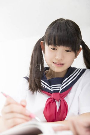 Foto de Sonriente estudiante japonés en uniforme escolar estudiando en la escuela - Imagen libre de derechos