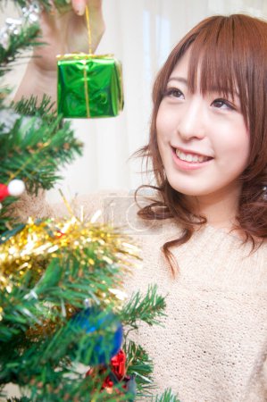 Photo for Asian woman decorating christmas tree - Royalty Free Image