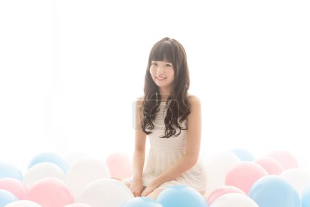 Photo for Happy asian woman sitting on the floor with balloons - Royalty Free Image