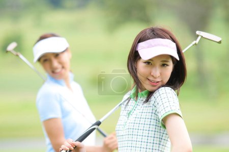 Téléchargez les photos : Deux femmes jouant au golf sur un parcours vert - en image libre de droit