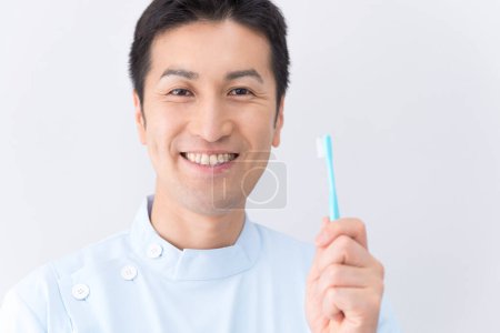 Téléchargez les photos : Jeune homme dentiste tenant une brosse à dents - en image libre de droit