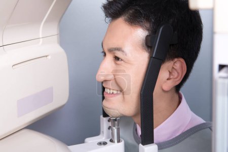 Foto de Asiático hombre está mirando a una máquina con una sonrisa, haciendo 3d imagen de mandíbulas - Imagen libre de derechos
