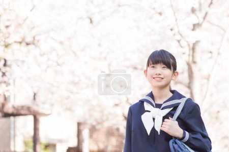 Foto de Retrato de un hermoso estudiante japonés en la calle con cerezos florecientes - Imagen libre de derechos