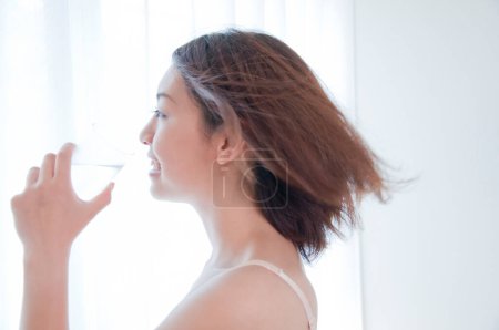 Téléchargez les photos : Portrait de belle jeune femme japonaise en lingerie blanche eau potable - en image libre de droit
