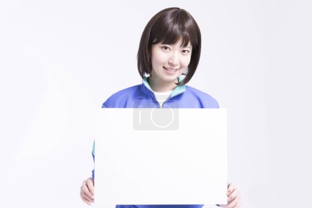 Téléchargez les photos : Jeune asiatique femme portant bleu survêtement tenant vide tableau blanc sur fond blanc - en image libre de droit