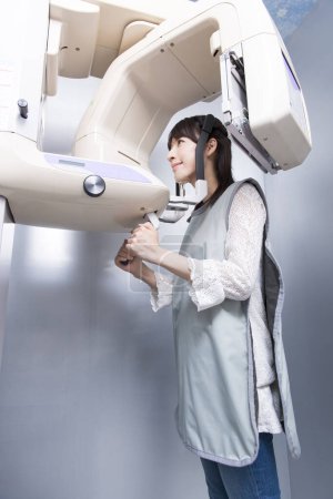 Foto de Paciente femenina haciendo tomografía computarizada dental. Mujer tomando rayos X de los dientes en la clínica con la ayuda de la máquina de rayos X de ortodoncia - Imagen libre de derechos