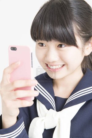 Foto de Retrato de joven asiática chica en uniforme escolar usando smartphone - Imagen libre de derechos