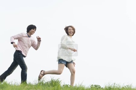 Photo for Happy young Asian couple running in summer park - Royalty Free Image