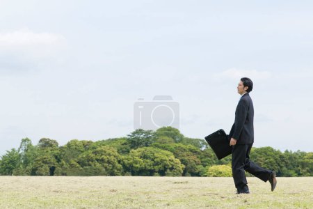 Foto de Asiático hombre de negocios caminar en el campo - Imagen libre de derechos