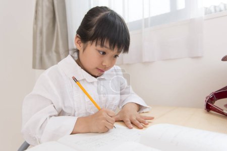 Téléchargez les photos : Petite fille asiatique faire des devoirs - en image libre de droit