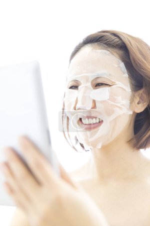 Téléchargez les photos : Portrait de belle femme japonaise mature avec masque facial hydratant sur fond blanc - en image libre de droit