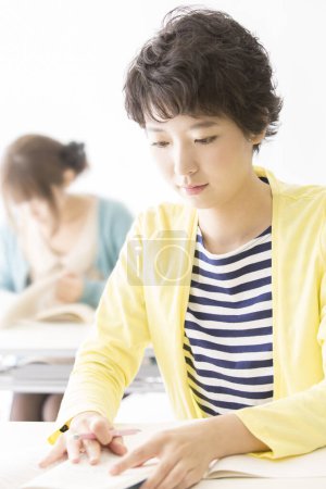 Téléchargez les photos : Étudiante femme écrire quelque chose en classe - en image libre de droit