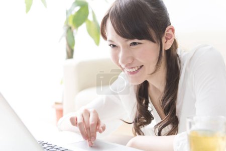 Téléchargez les photos : Asiatique jeune femme en utilisant ordinateur portable à la maison - en image libre de droit