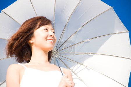 Foto de Hermosa mujer asiática posando en la playa con paraguas - Imagen libre de derechos