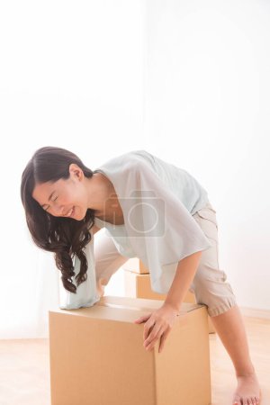 Photo for Asian woman with cardboard box moving into new apartment - Royalty Free Image