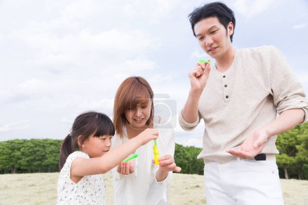 Foto de Asiático familia madre, padre y hija soplando jabón burbujas - Imagen libre de derechos