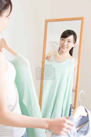 Téléchargez les photos : Femme choisissant les vêtements par miroir - en image libre de droit