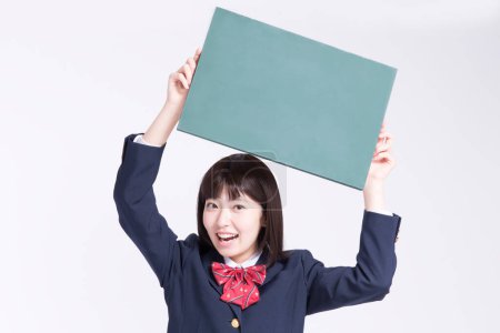 Photo for Young asian schoolgirl showing blank green board on white background - Royalty Free Image