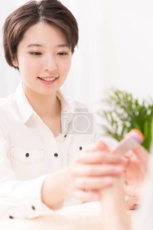 Foto de Hermosa mujer japonesa haciendo manicura en salón de belleza - Imagen libre de derechos