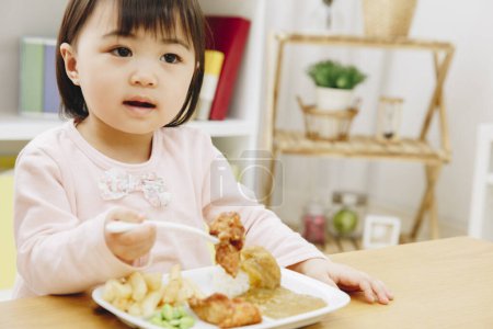 Téléchargez les photos : Mignonne asiatique fille manger japonais nourriture à la maison - en image libre de droit