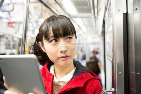 Photo for Asian woman using a tablet in the subway - Royalty Free Image