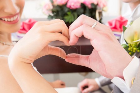 Photo for Beautiful young wedding couple showing hand heart gesture - Royalty Free Image