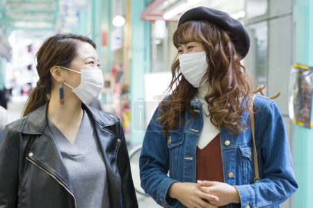 Téléchargez les photos : Jeunes femmes avec des masques de protection dans la rue - en image libre de droit