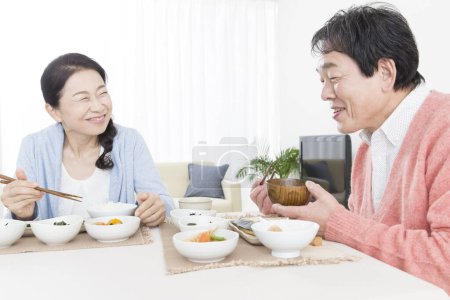 Photo for Senior asian couple having meal in kitchen - Royalty Free Image