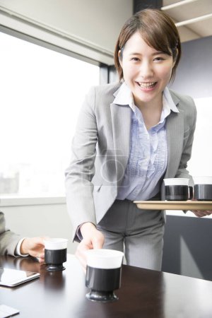 Photo for Young asian business woman with coffee cups in office - Royalty Free Image