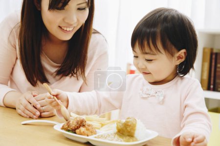 Photo for Cute Asian girl with mother eating Japanese food  at home - Royalty Free Image