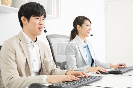 Photo for Two young asian business people in headsets in office - Royalty Free Image
