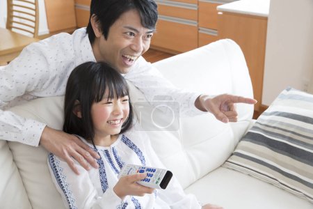 Téléchargez les photos : Jeune père et sa petite fille regarder la télévision - en image libre de droit