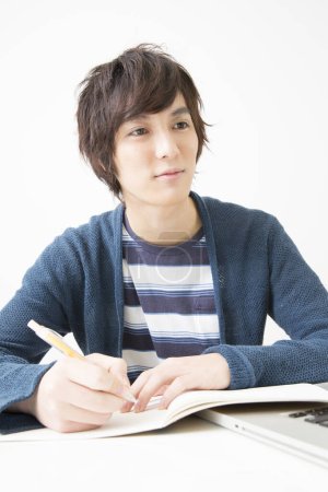 Téléchargez les photos : Asiatique étudiant écriture sur notebook à bureau - en image libre de droit