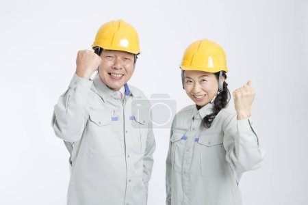 Téléchargez les photos : Les travailleurs âgés asiatiques montrant les poings debout sur le mur blanc. - en image libre de droit