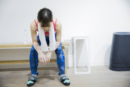 Téléchargez les photos : Jeune femme asiatique assis sur le banc à la salle de gym. - en image libre de droit