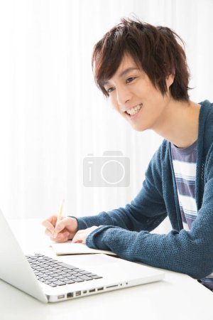 Photo for Asian male student studying at desk - Royalty Free Image