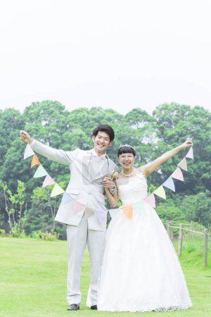Téléchargez les photos : Jeune couple de jeunes mariés avec guirlande dans le parc - en image libre de droit
