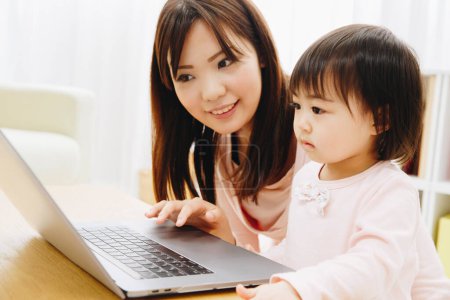 Foto de Primer plano hermosa asiática madre y hija usando laptop - Imagen libre de derechos