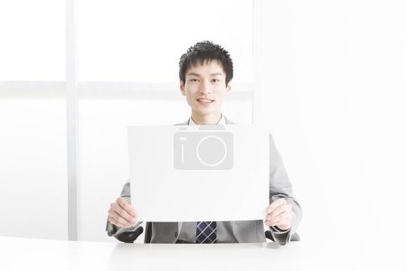 Photo for Close-up portrait of young japanese businessman showing blank placard - Royalty Free Image