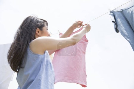 Foto de Joven japonesa mujer colgando ropa en la cuerda al aire libre - Imagen libre de derechos