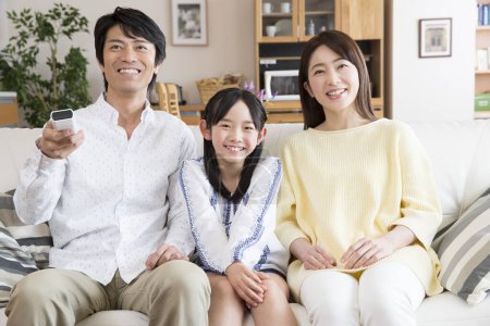 Téléchargez les photos : Asiatique famille de trois regarder la télévision - en image libre de droit