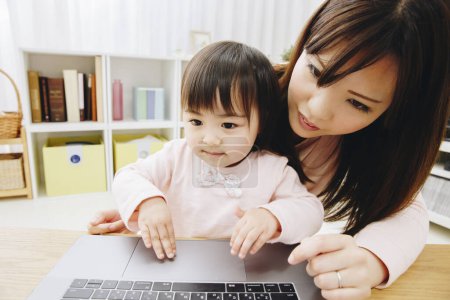 Photo for Young mother and little daughter with laptop at home - Royalty Free Image
