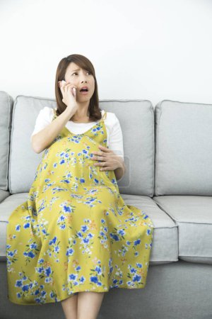 Téléchargez les photos : Portrait de jeune asiatique enceinte femme en utilisant smartphone - en image libre de droit