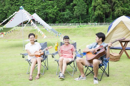 Foto de Feliz asiático amigos jugando instrumentos musicales en camping park - Imagen libre de derechos