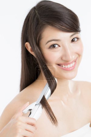 Photo for Beautiful  japanese woman curling long hair using curling iron. - Royalty Free Image