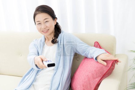 Photo for Woman holding tv remote control - Royalty Free Image